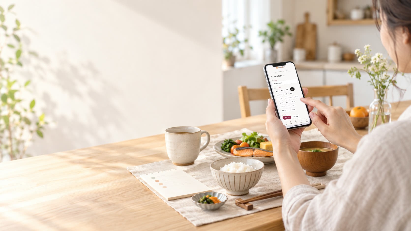 朝の食卓で、グルメBookの記録画面を開いたスマートフォンを手にしている人